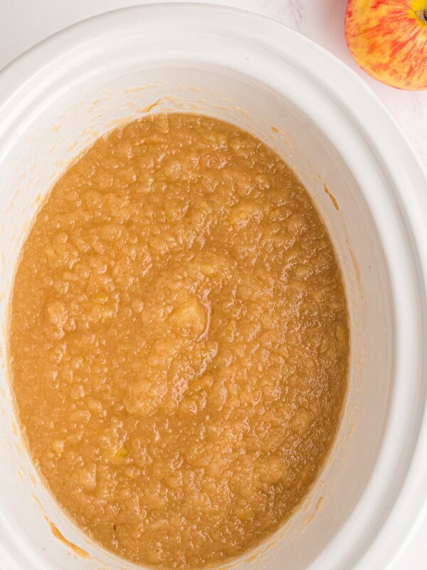 close up of applesauce cooked in a white slow cooker.