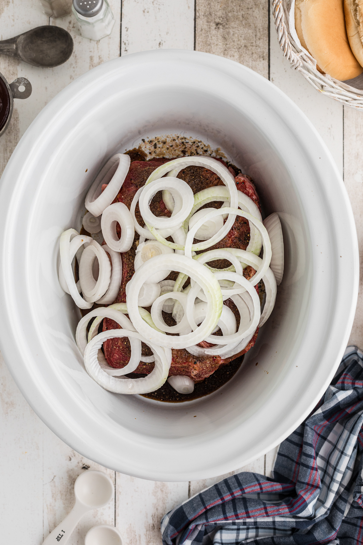 onions added on top of a chuck roast in a crockpot.