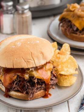 two plated slow cooker arby's beef and cheddar sandwiches.