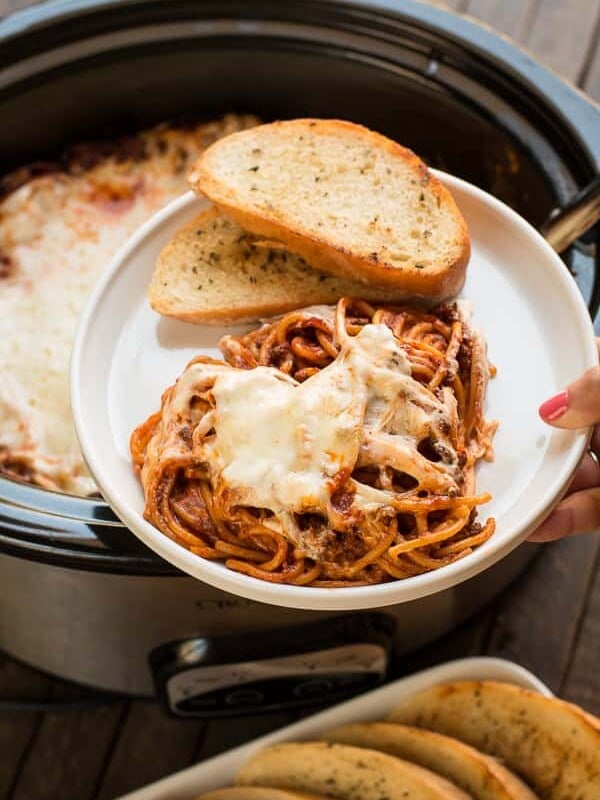plate with baked spaghetti with cheese, garlic butter on the side.