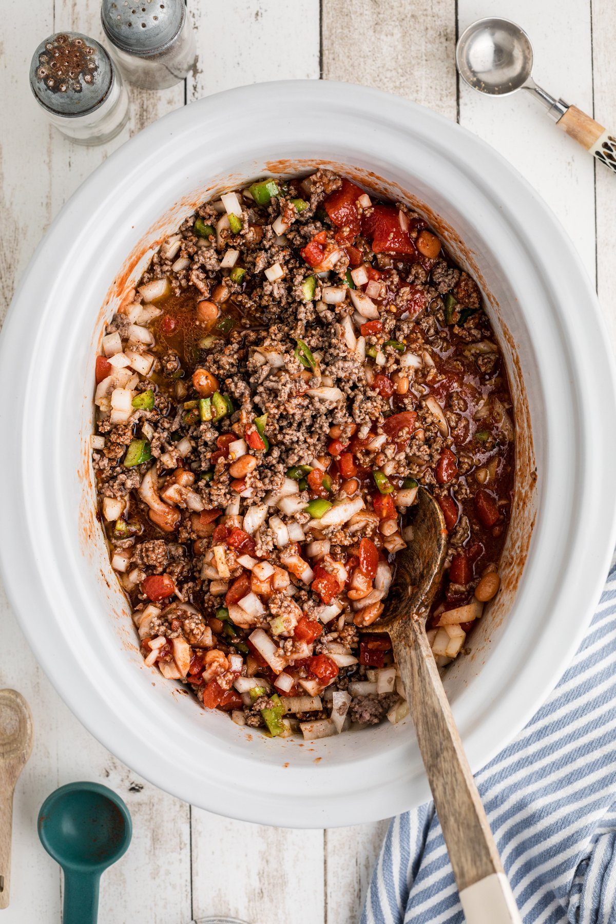 Ingredients for chili in a slow cooker being stirred.