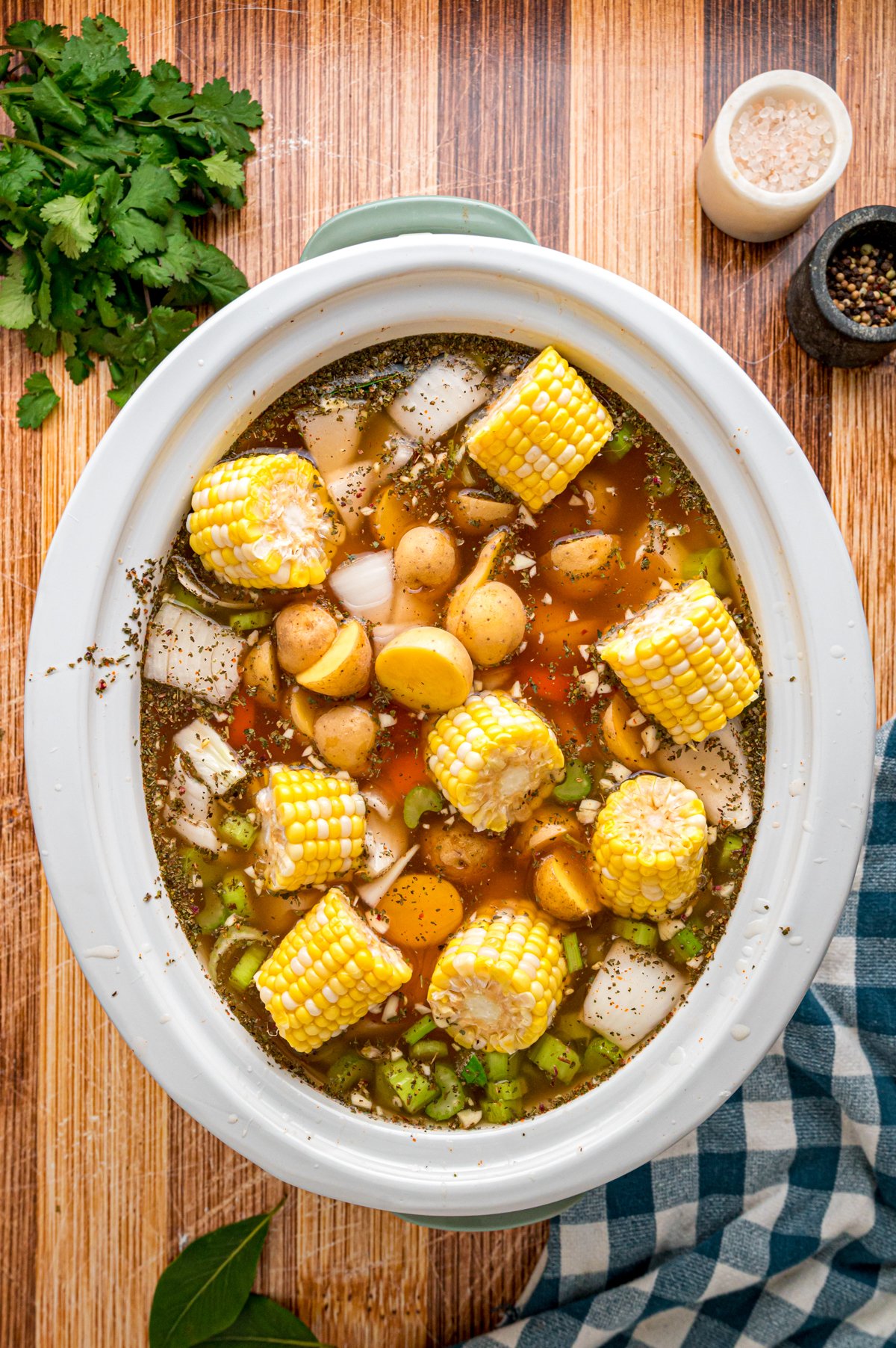 Carrots, celery, potatoes, onion, and corn added to the slow cooker.