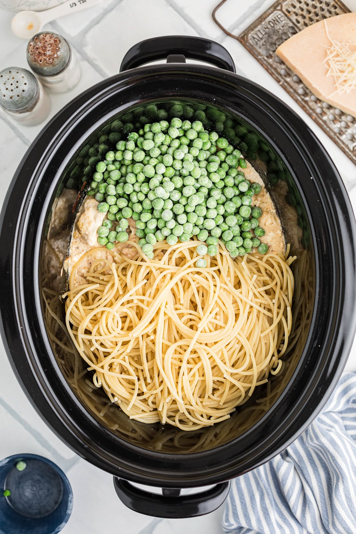 Spaghetti and peas added to a crockpot.