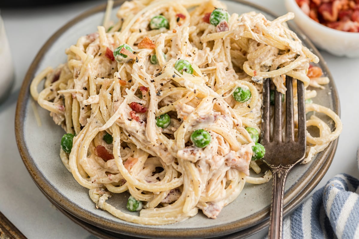 A plate of slow cooker chicken carbonara with a fork.