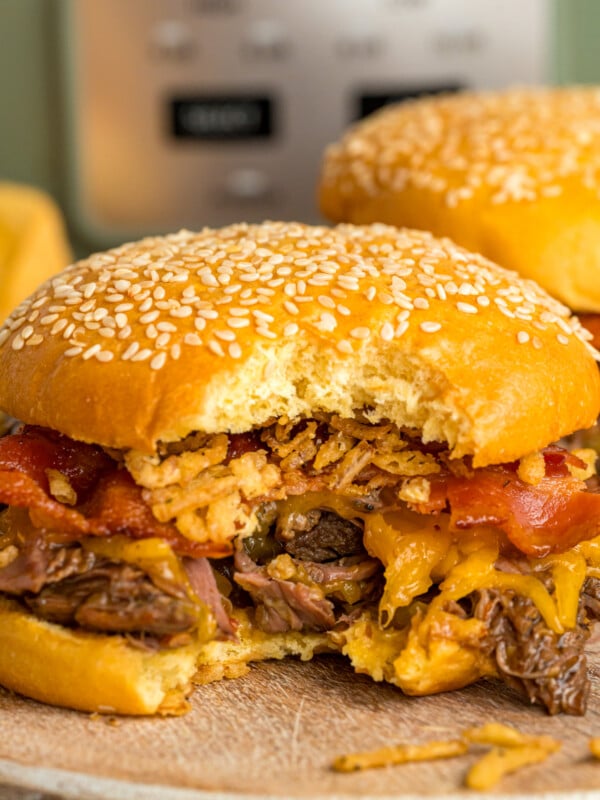 Slow cooker cowboy sandwiches on a serving dish with a bite taken out of one.