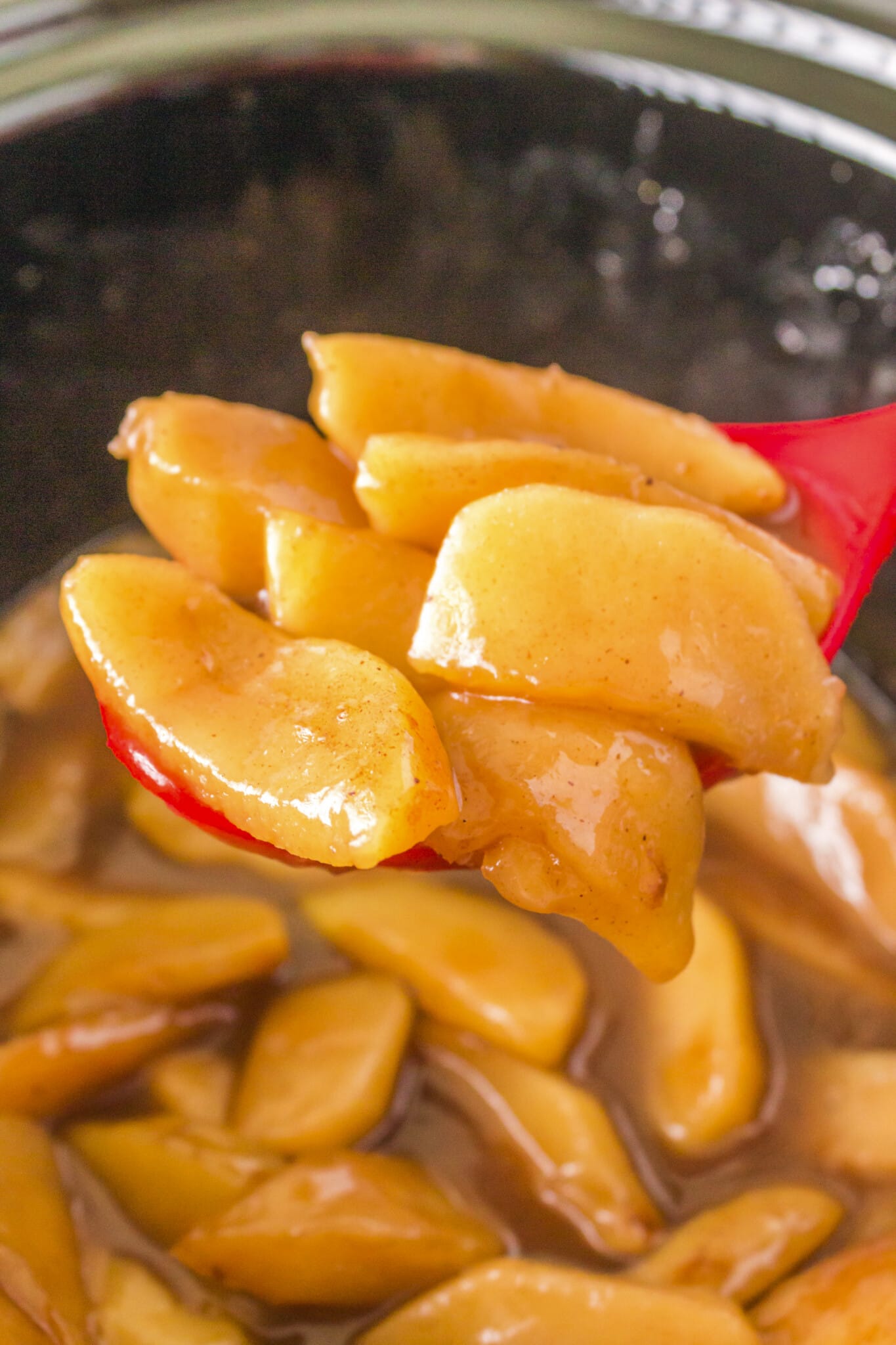 fried apples on a spoon coming from crockpot