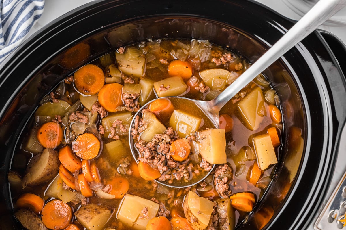 Close-up of ladle scooping out some slow cooker hobo soup.