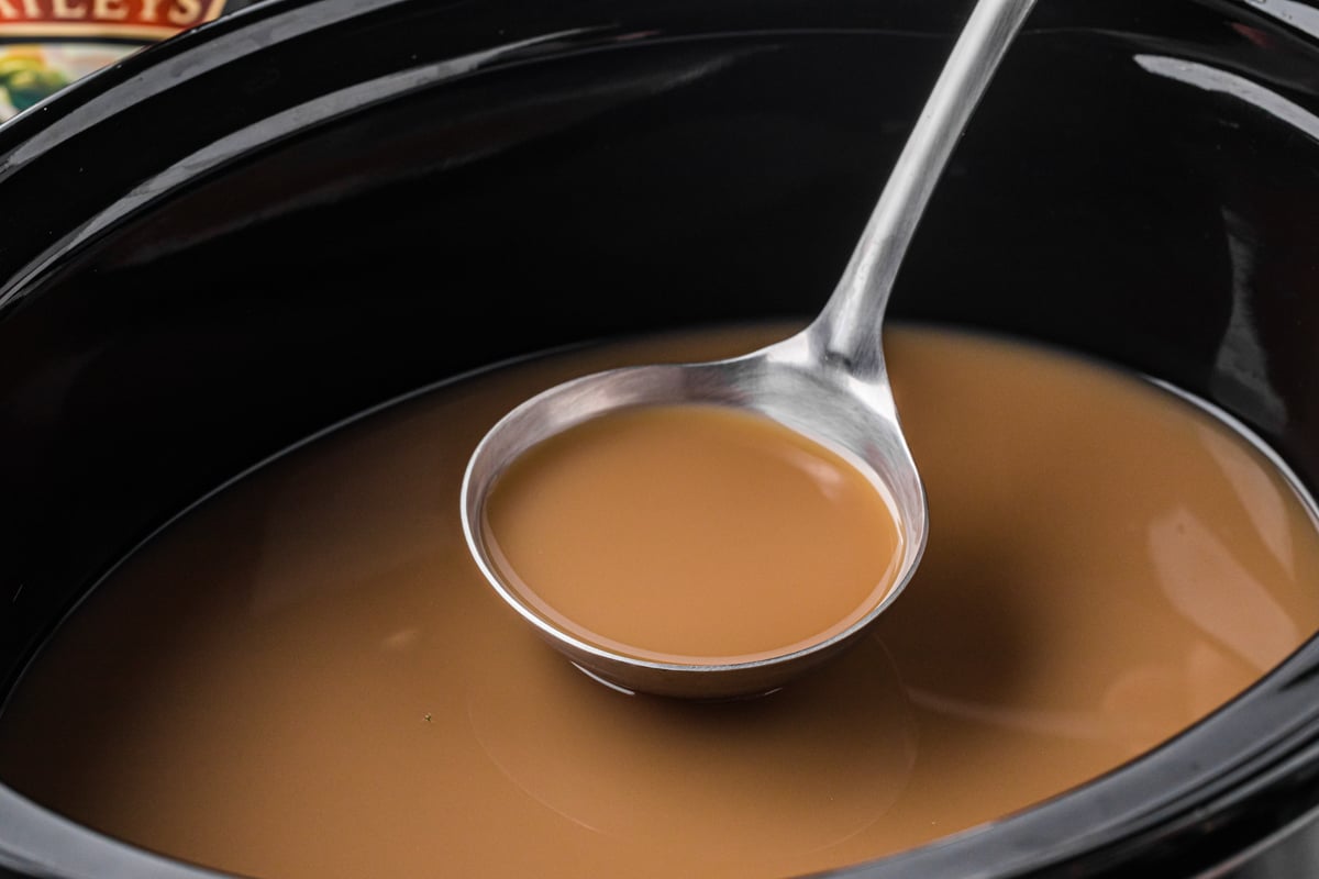Ladle scooping out some slow cooker hot buttered rum coffee.