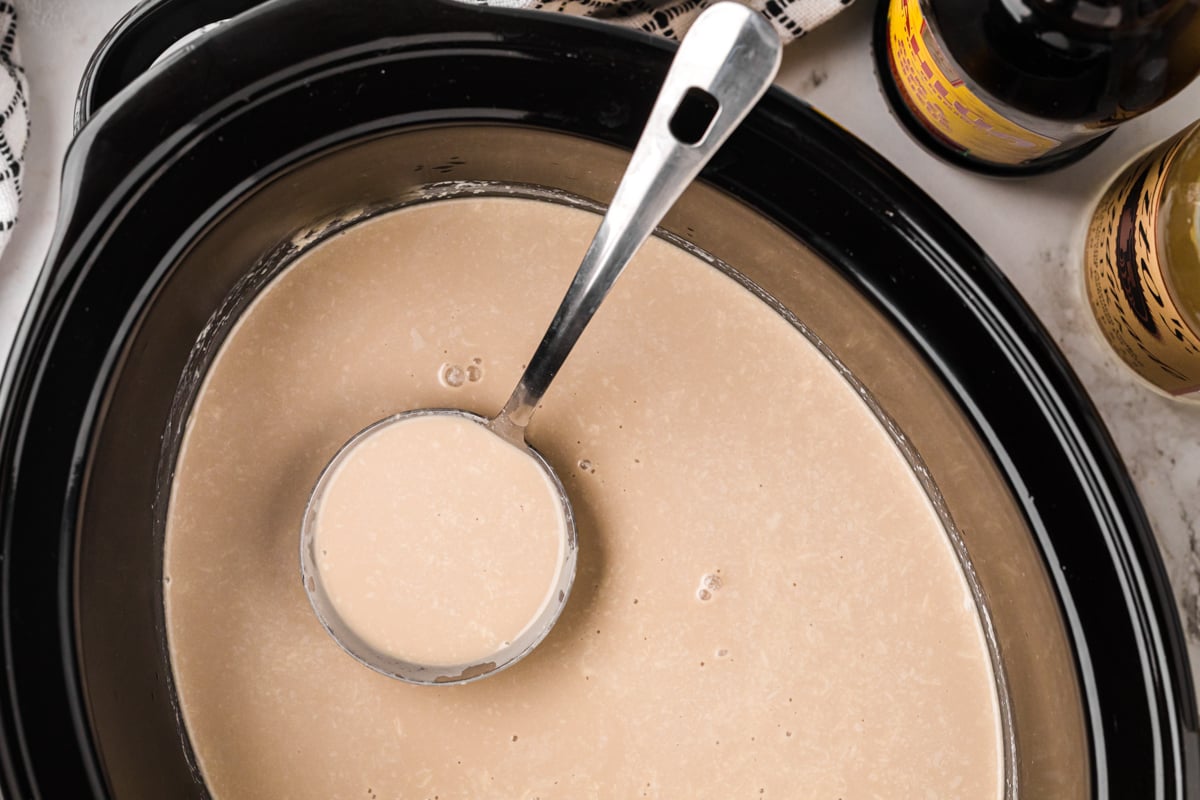 overhead of ladle scooping out slow cooker hot white russians.