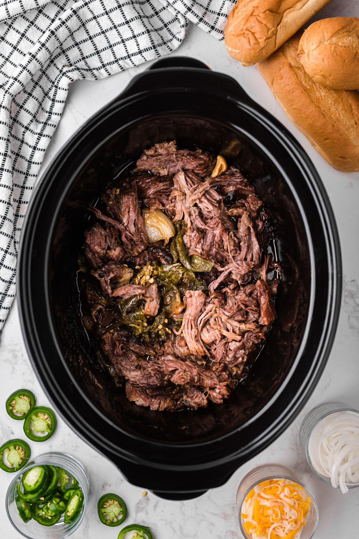 Shredded beef and jalapenos for sandwiches in a crockpot.