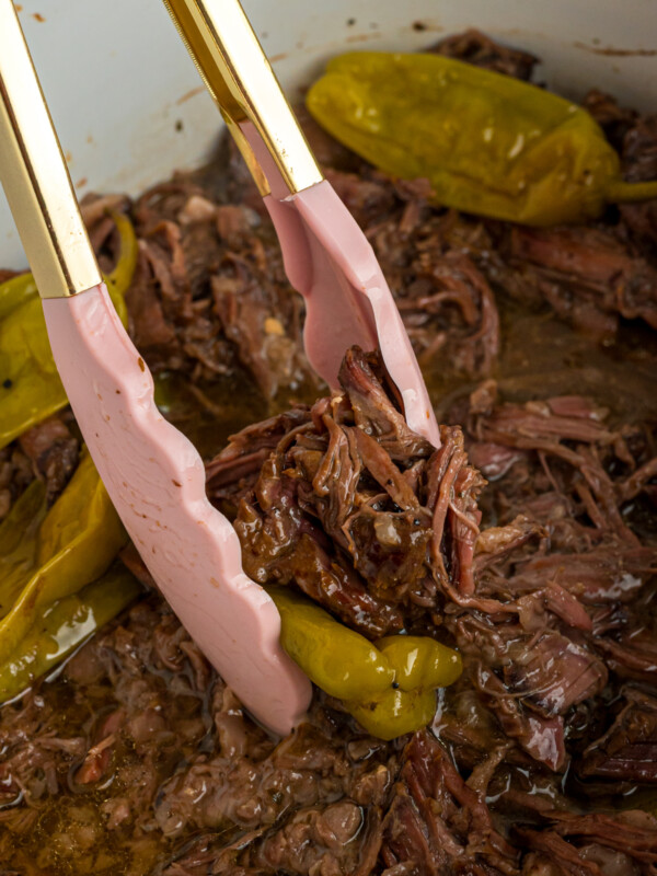 tongs taking out some of the slow cooker Mississippi pot roast.