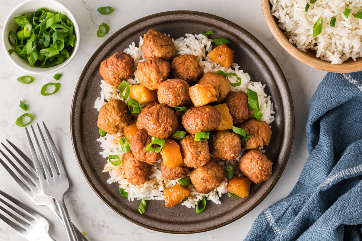 Pineapple meatballs over white rice on a plate.