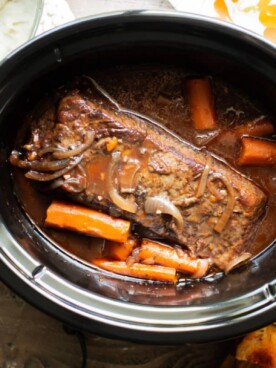 finished cooking brisket in the slow cooker with mashed potatoes and carrots on the side.