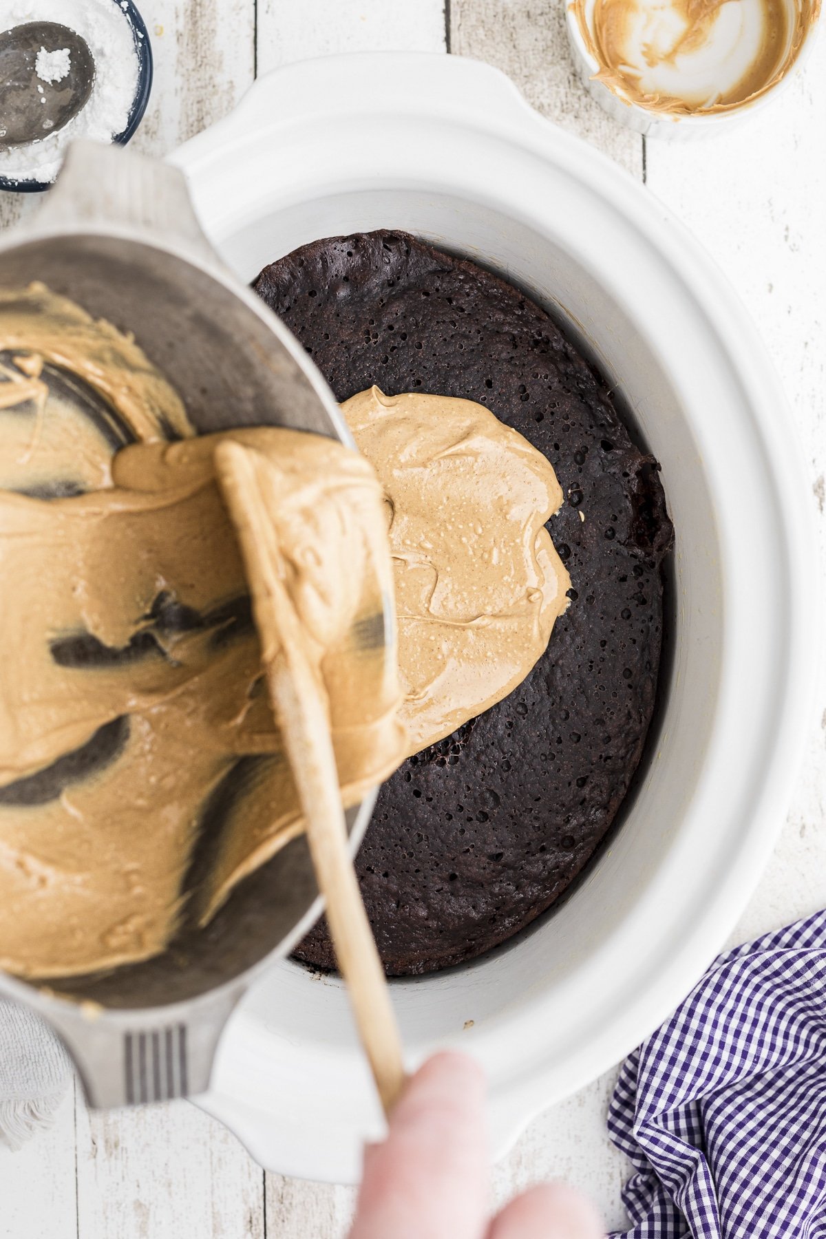 peanut butter frosting being poured over chocolate cake.