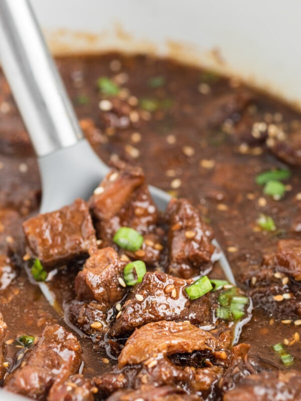 scooping teriyaki beef out of a crockpot.